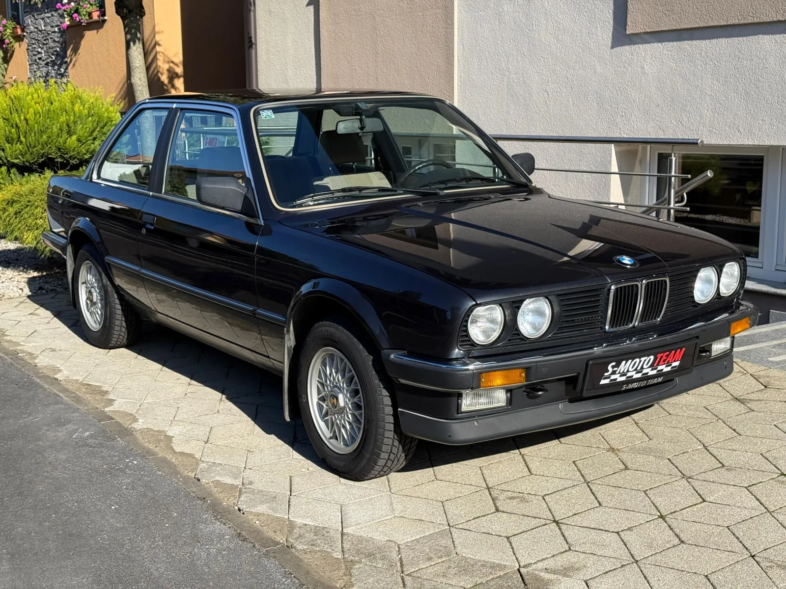 BMW 320i E30 u crnoj boji - pogled ukoso s druge strane