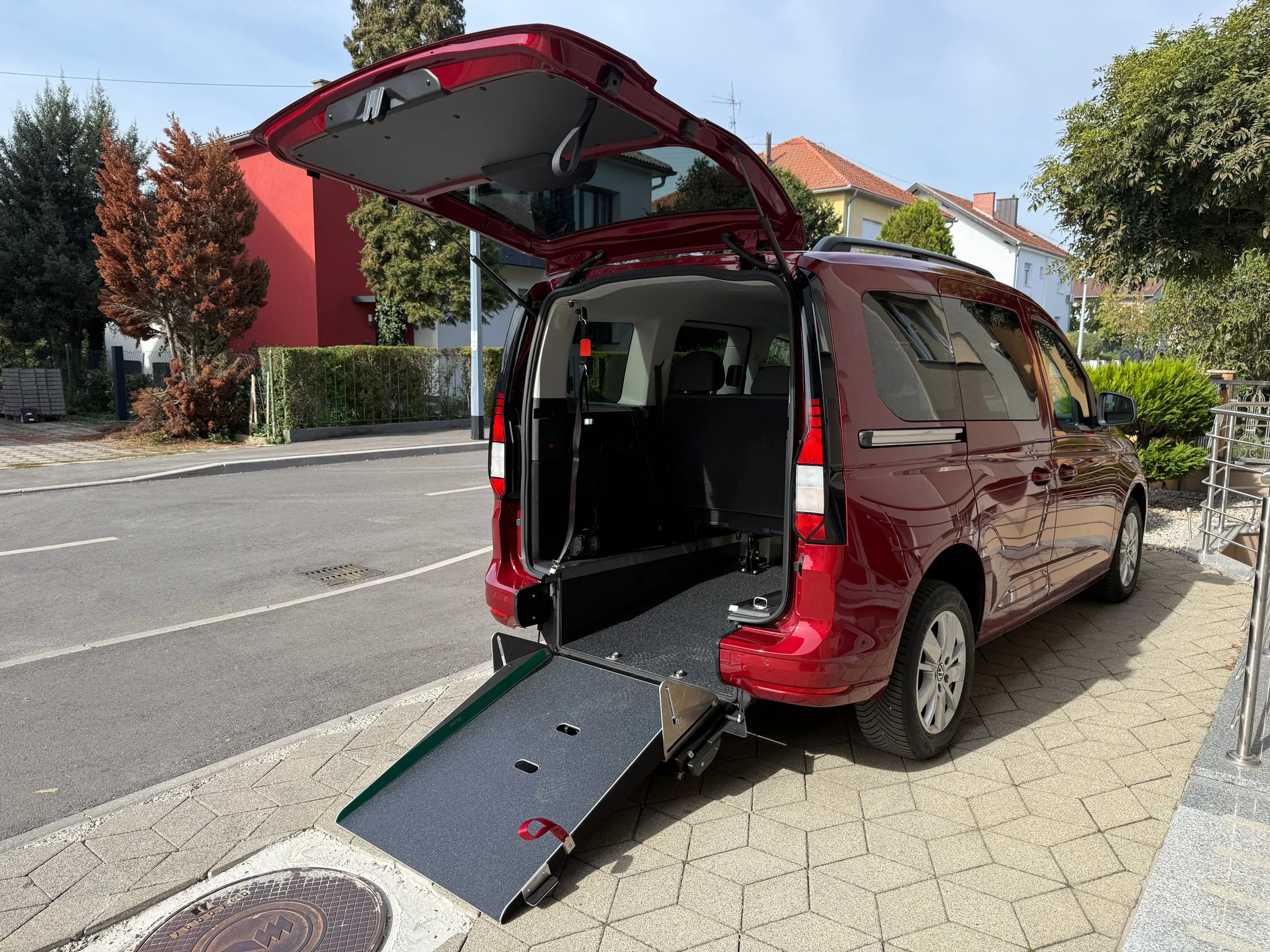 Volkswagen Caddy u crvenoj boji, prilagođen za invalidska kolica - otvorena stražnja vrata i spuštena rampa