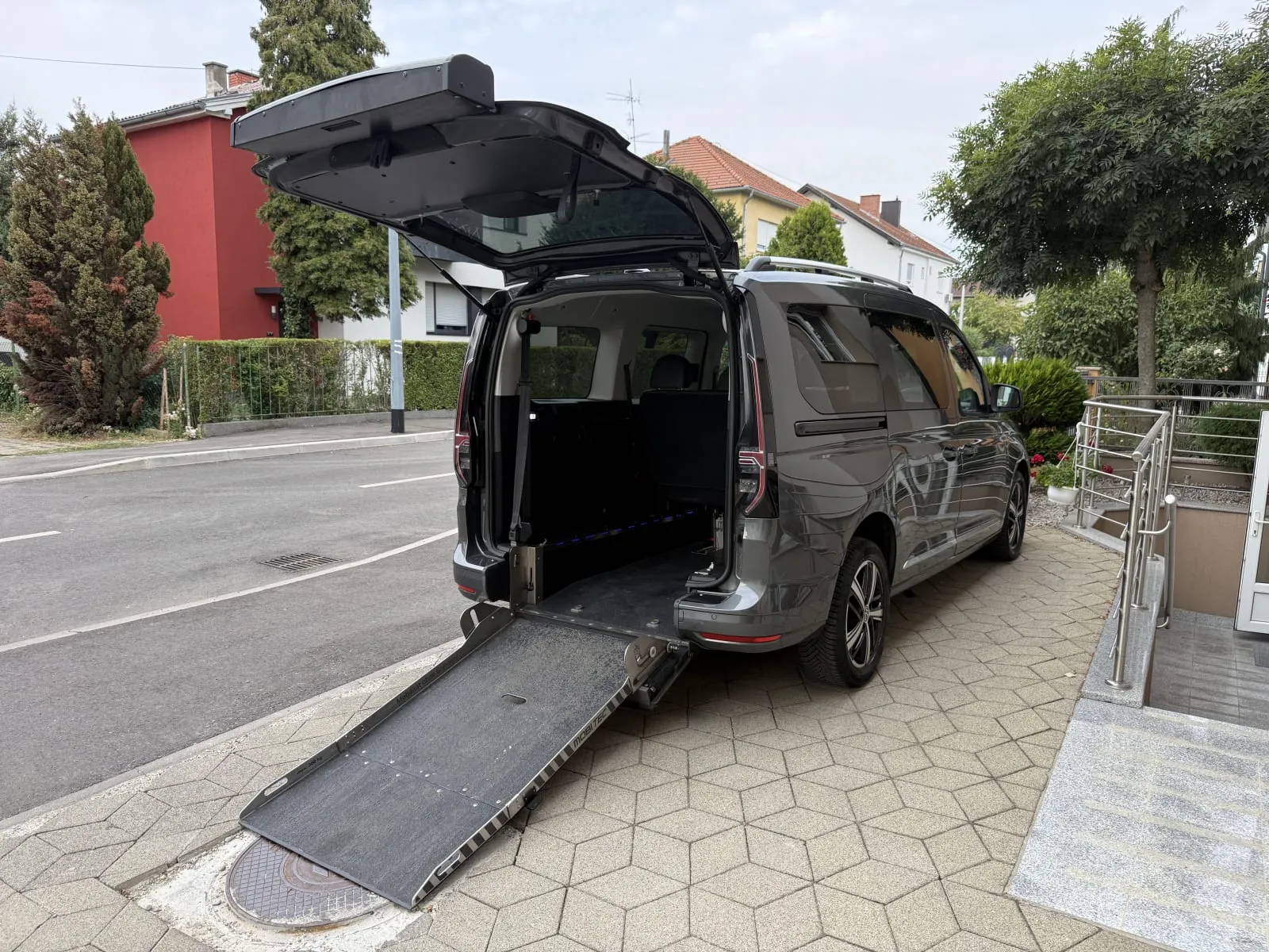 Volkswagen Caddy Maxi u sivoj boji, prilagođen za invalidska kolica - otvorena stražnja vrata i spuštena rampa