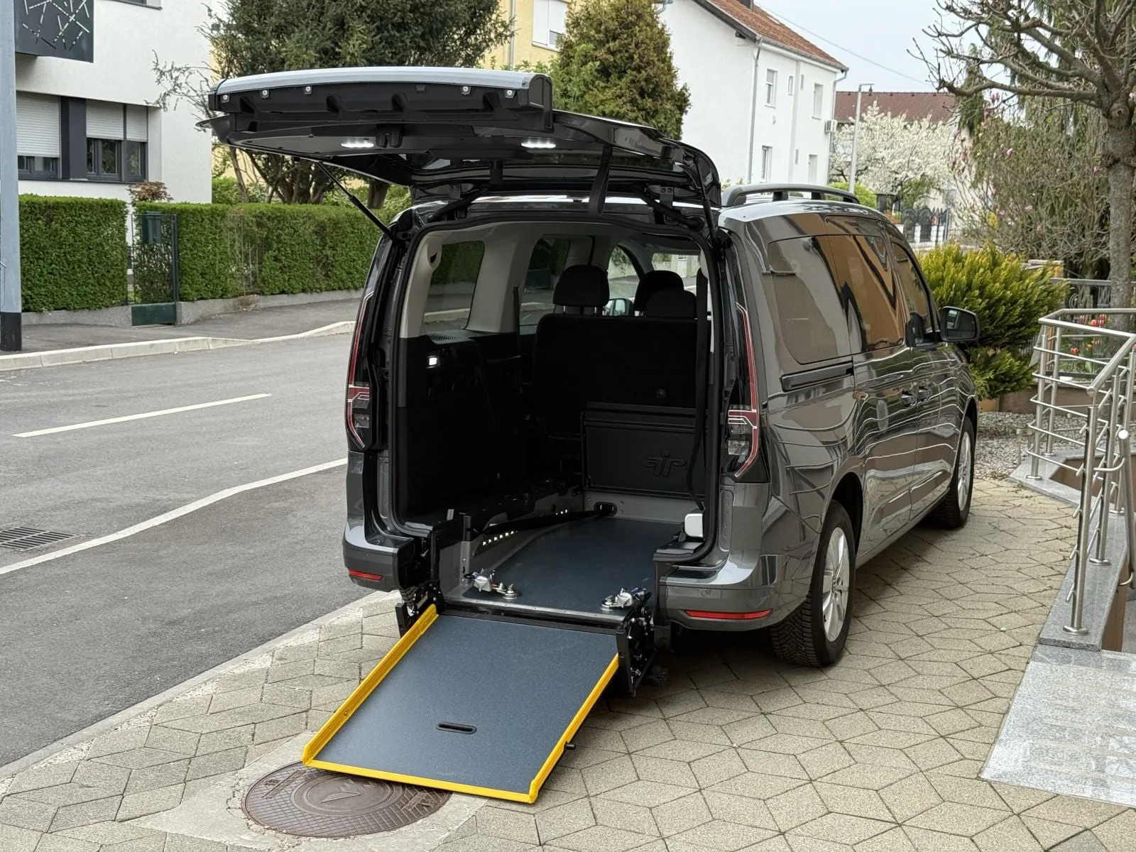 Volkswagen Caddy Maxi u sivoj boji, prilagođen za invalidska kolica - otvorena stražnja vrata i spuštena rampa